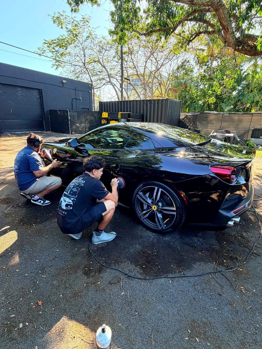 Two Highclass technicians machine polishing a black Ferrari Portofino